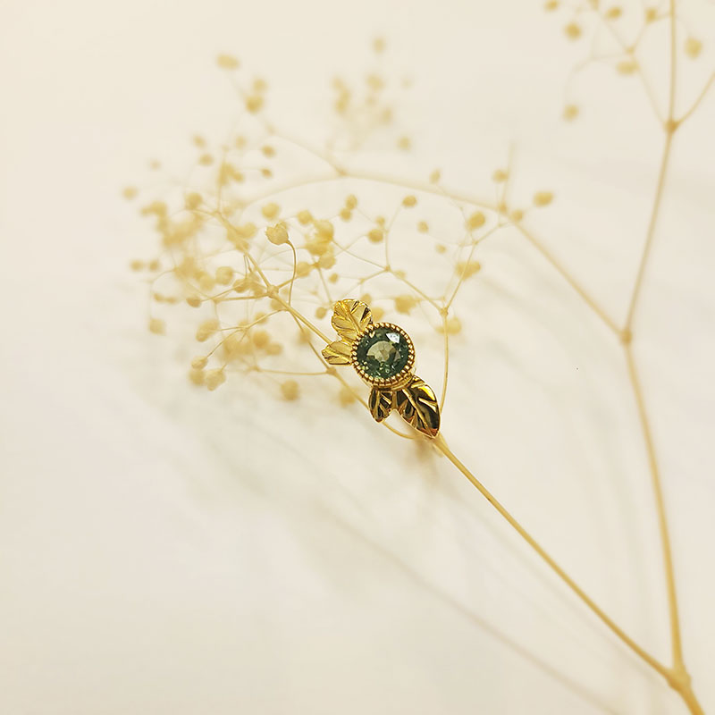 Bague créée artisanalement à Lyon. Anneau or jaune et saphir vert. Thème végétal pour cette élégante bague.