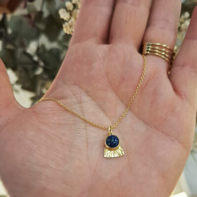 Pendentif "Rê", symbole du soleil en or jaune 18 carats et lapis lazuli. le pendentif est suspendu à une chaîne fine. Fabrication par la bijoutière Sophie Mouleyre à Lyon.